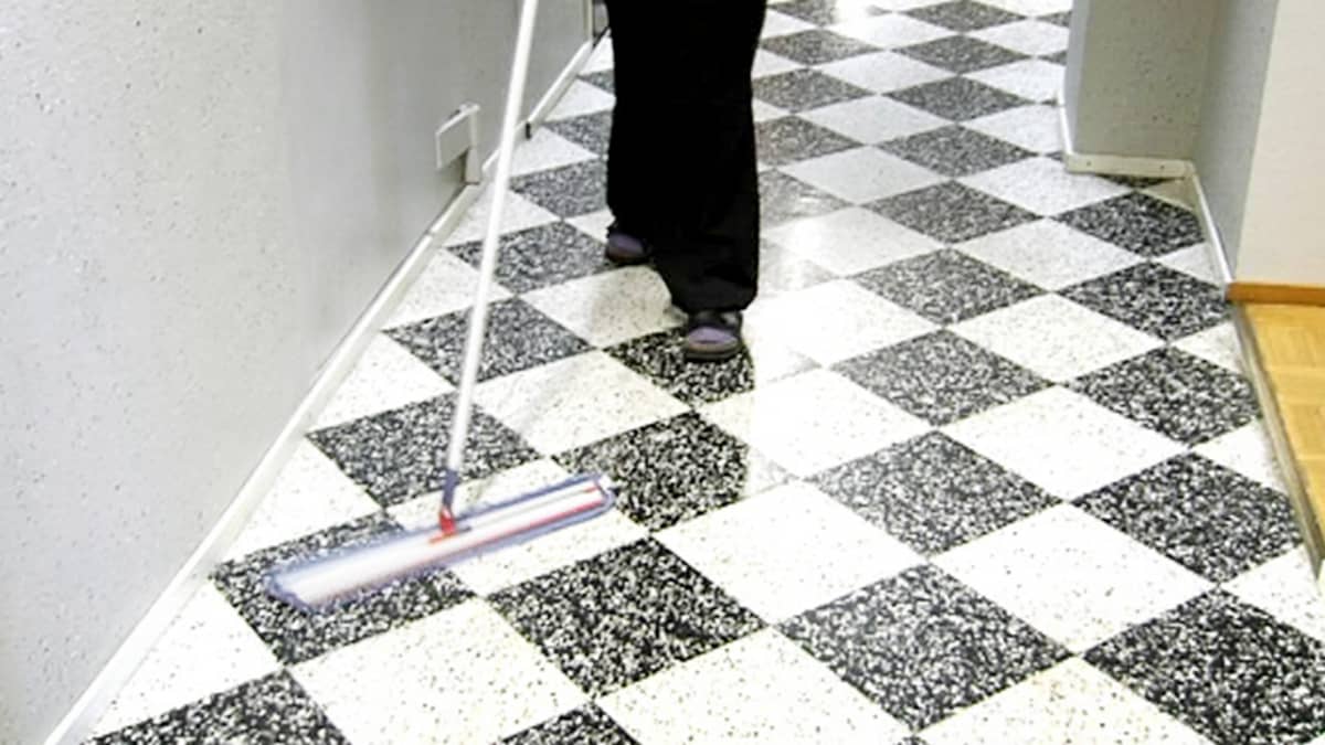 Nainen siivoaa käytävän lattiaa.