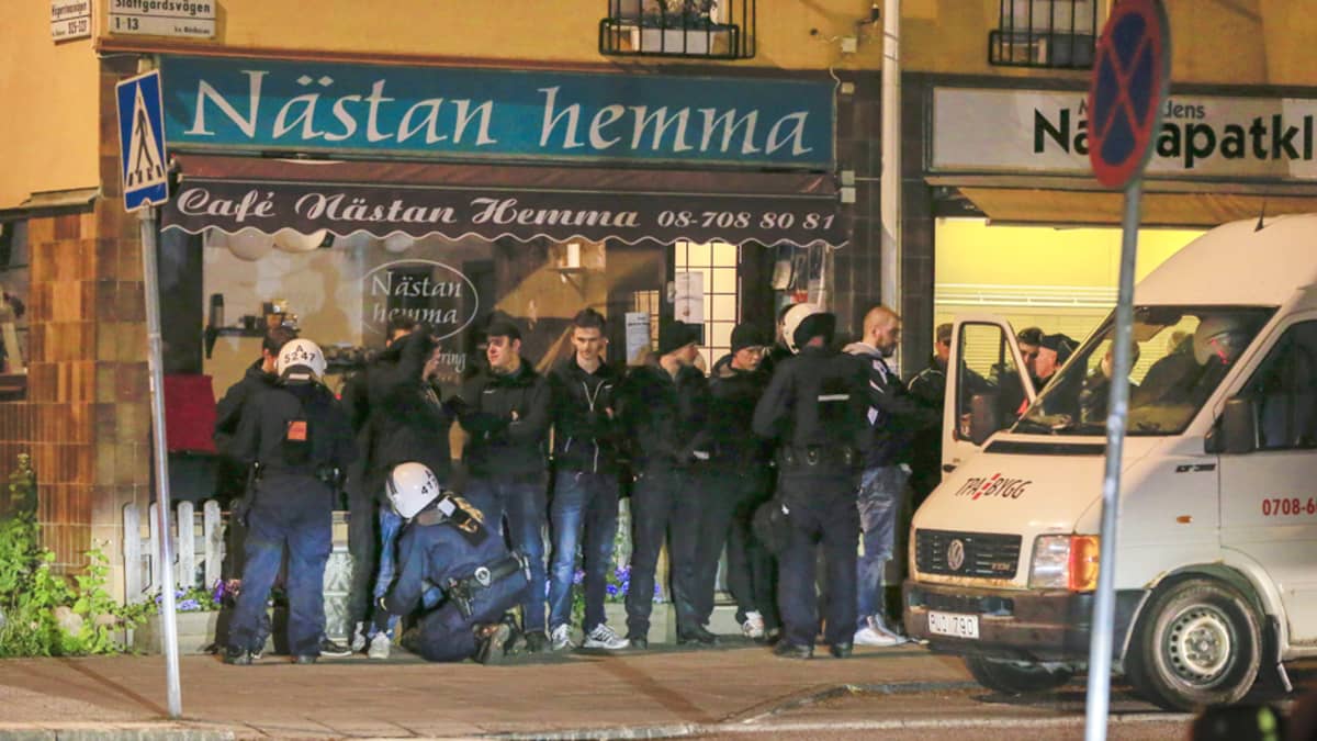Mellakkapoliisi jututti miesjoukkiota Hägerstenin kaupunginosassa Tukholmassa varhain toukokuun 25. päivän aamuna. 