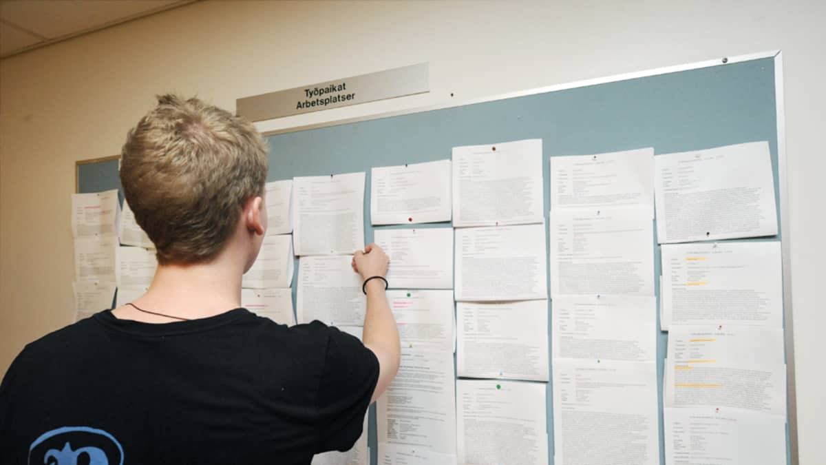 Nuori mies tutkii ilmoitustaulua työnhakukeskuksessa Helsingissä.