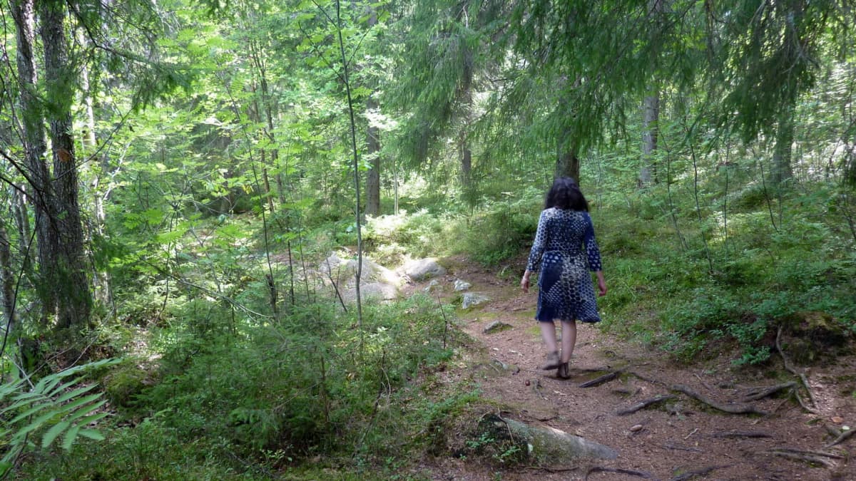 Nainen kävelee metsässä. 