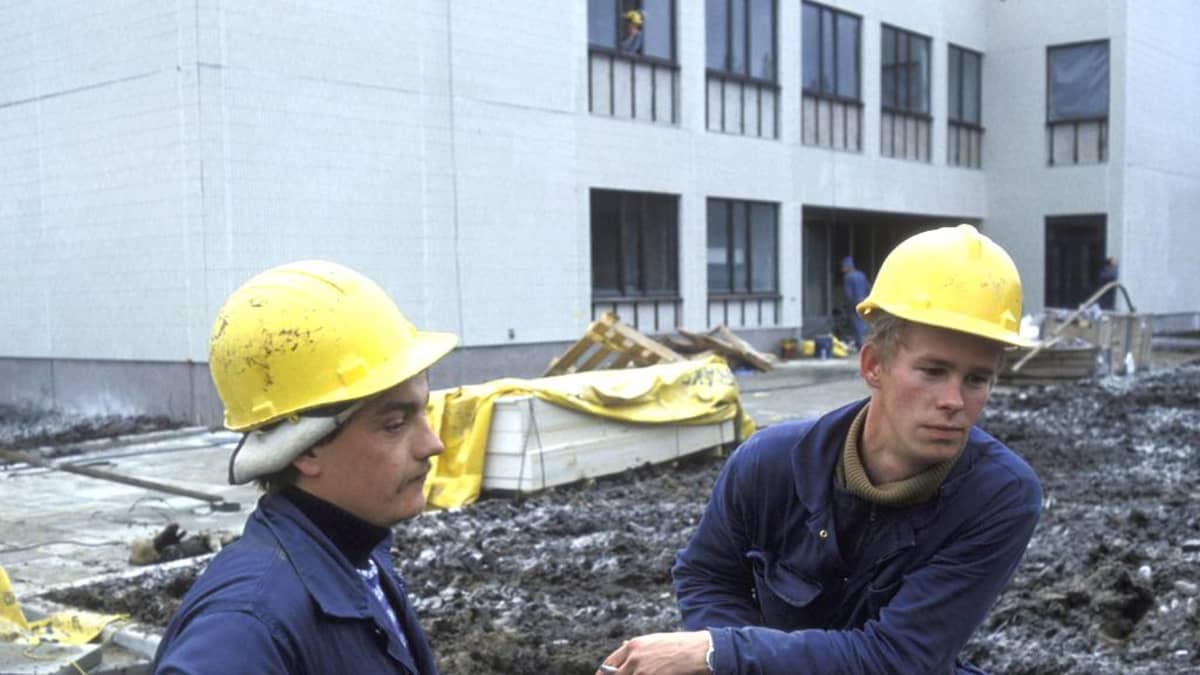 Kuva otettu Kostamuksessa 14.10.1981, kahdella suomalaisella rakennusmiehellä on siniset haalarit ja keltaiset turvakypärät.