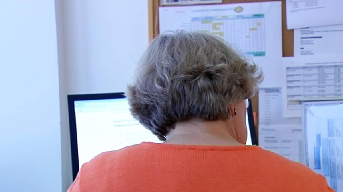 Noin kuusikymppinen nainen tietokoneen äärellä toimistossa.