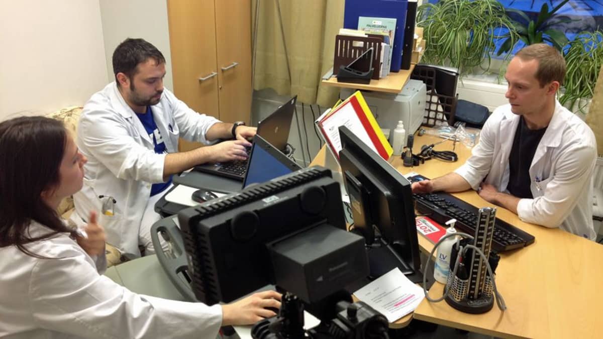Lääkäreitä tutkimassa potilasasiakirjoja tietokoneelta.