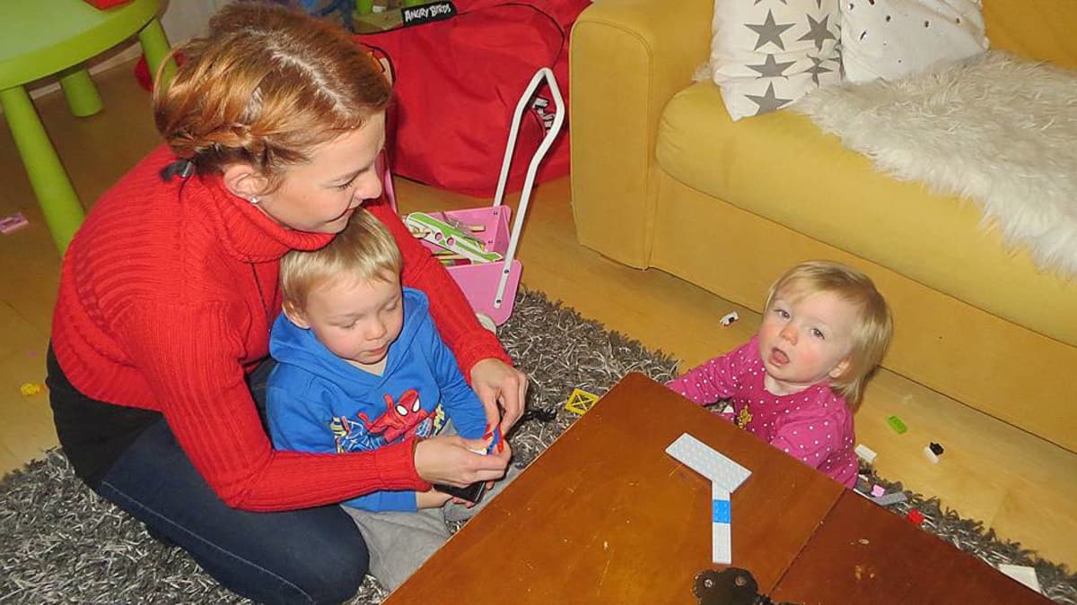Äiti ja lapset leikkivät lattialla.