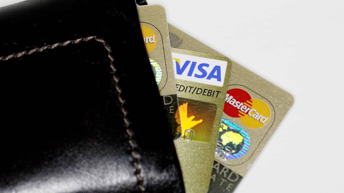 Kuvassa lompakko, joka pursuaa luottokortteja.