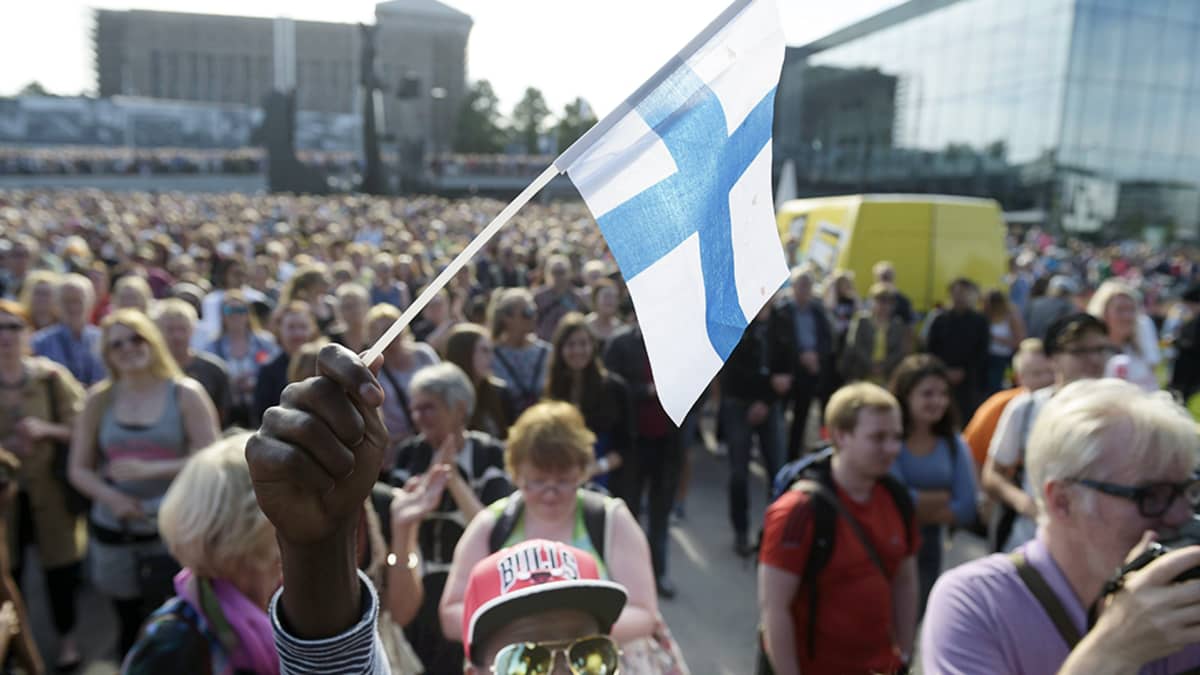 Mire Ibrahim heiluttaa Suomen lippua monikulttuurisuutta puolustavassa mielenosoituksessa Helsingin Kansalaistorilla.