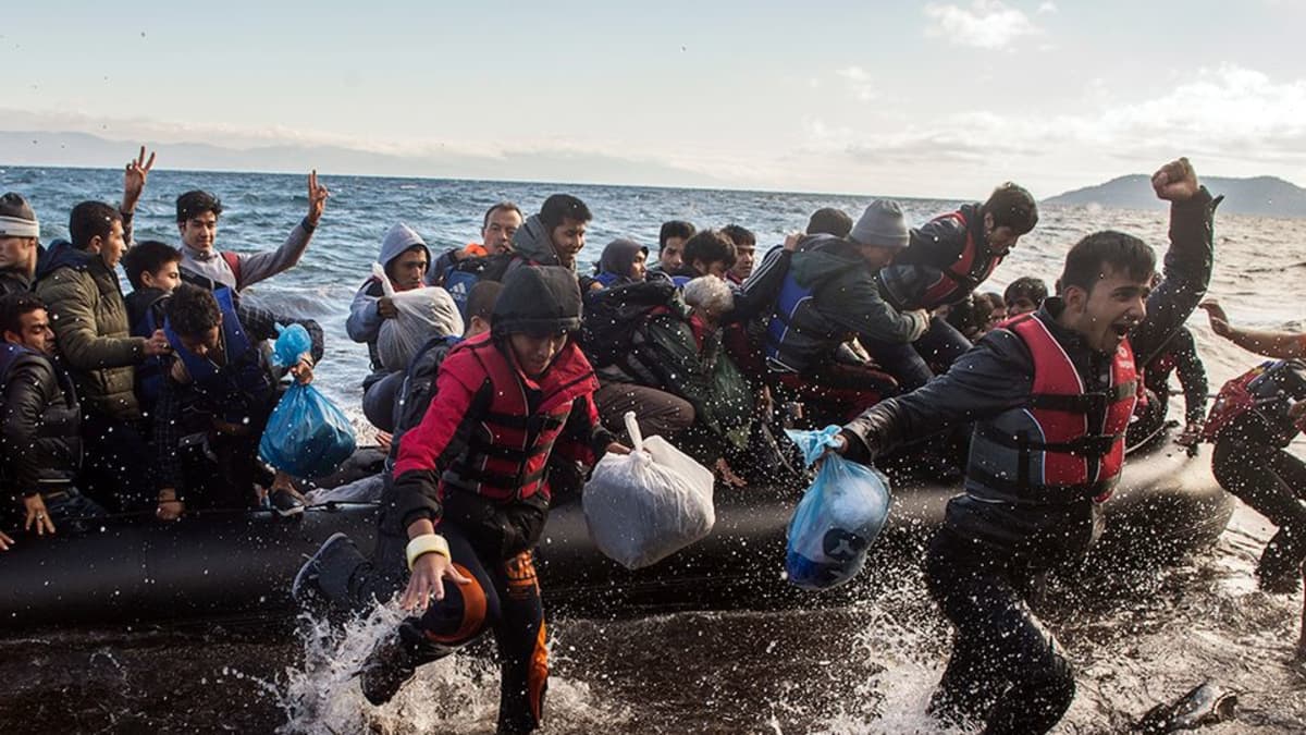 Pakolaiset iloitsevat selviydyttyään merimatkasta Lesboksen saarelle.