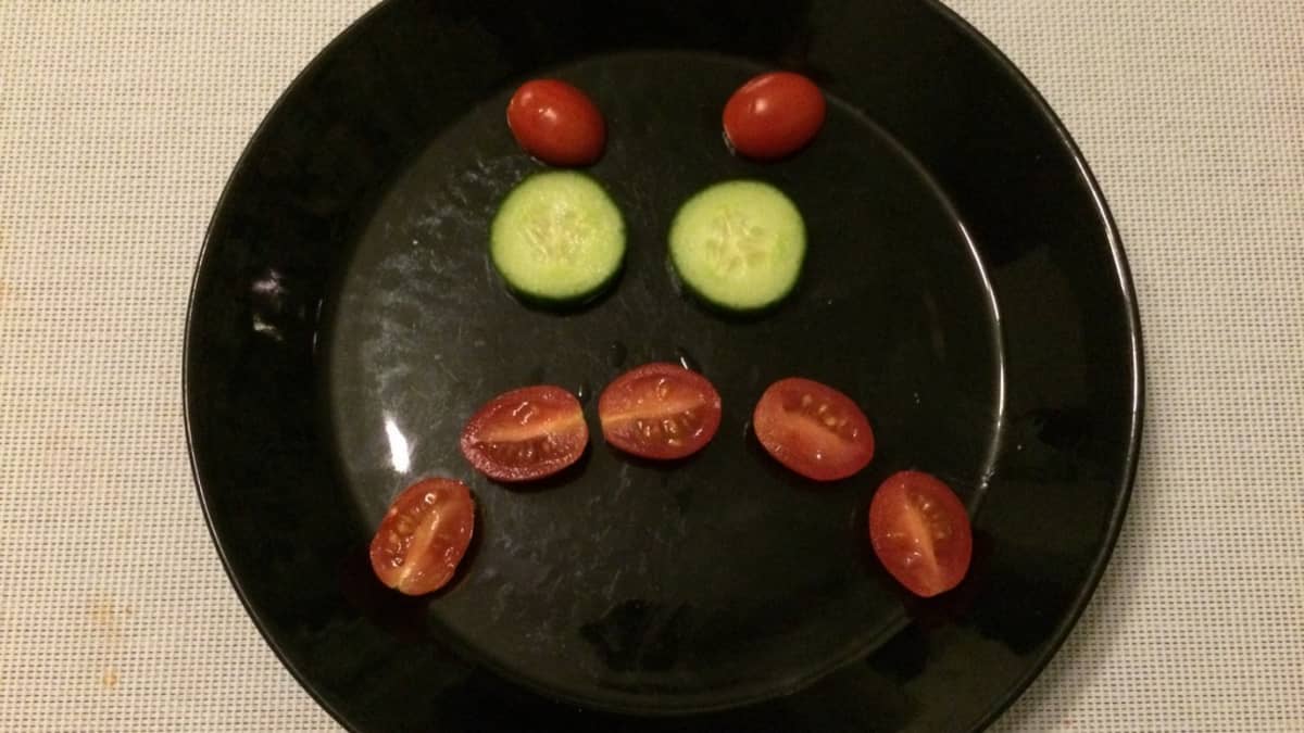 Kurkkuviipaleista ja tomaateista tehty vihainen naama lautasella.