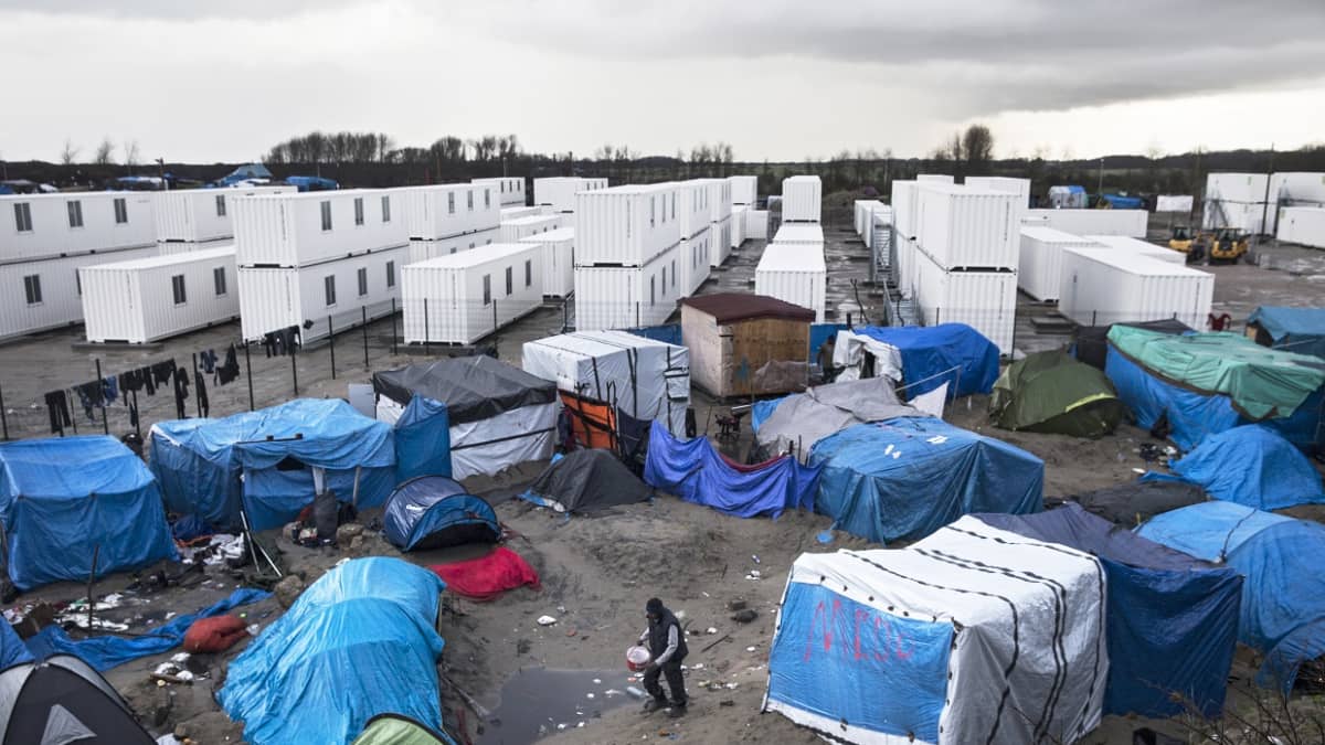 Valkoisia kontteja Calais'n teltoista koostuvan siirtolaisleirin takana Pohjois-Ranskassa.