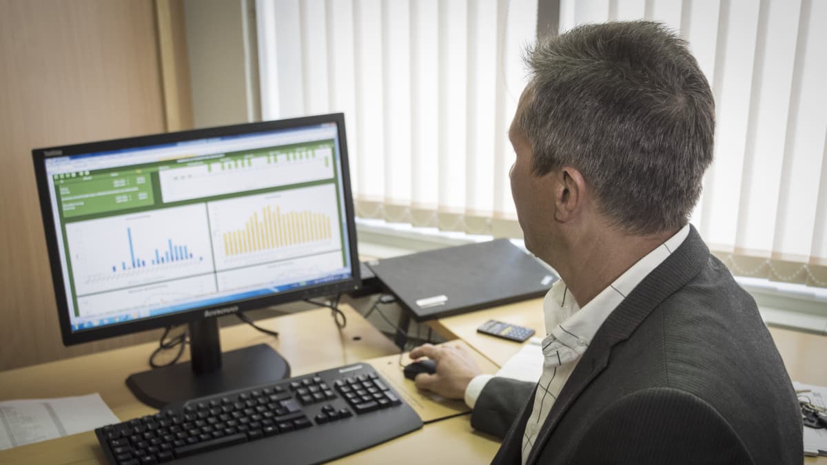 Tekninen päällikkö Markus Snellman näyttää tietokoneen näytöltä tehtaan energiankulutusta esittäviä taulukoita. 