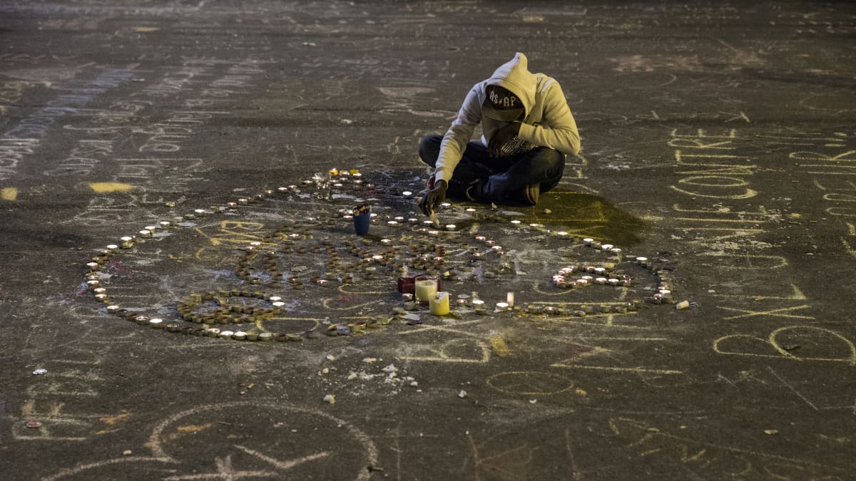 Nuori mies sytyttää kynttilöitä Place de la Boursen aukiolla Brysselissä uhrien muistoksi.