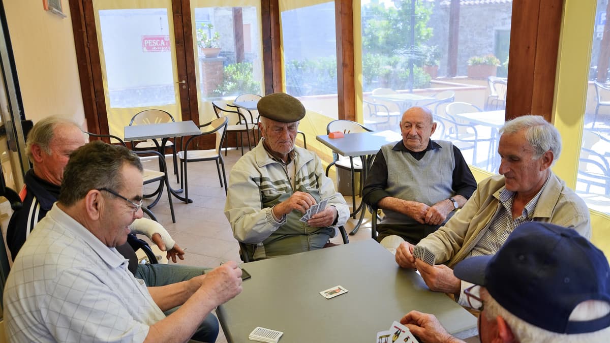 Miehet pelaavat korttia. Acciarolin kylän miehet kokoontuvat iltapäivisin pelaamaan korttia ja juoruamaan.