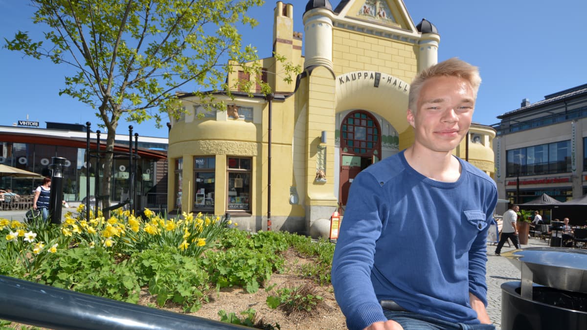 Jalkapalloilija Ilmari Niskanen istuu Kauppahallin edessä.