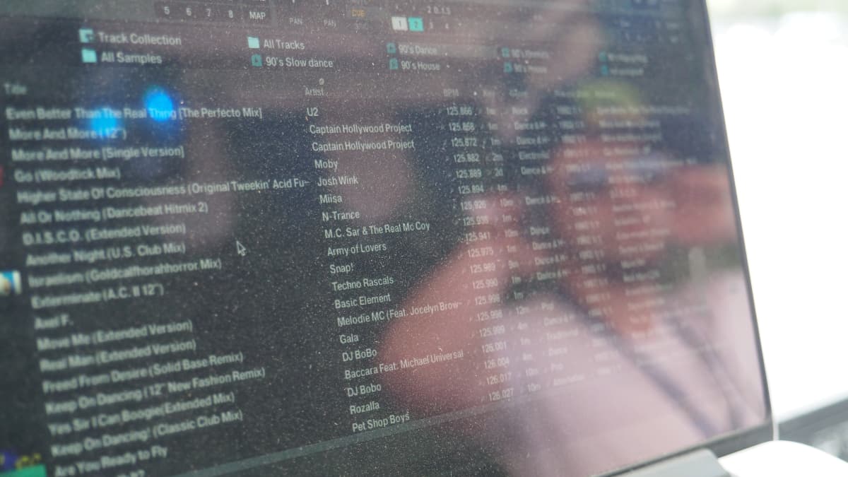 Tietokoneen näyttö, jossa lista 90-luvun musiikkia. Näytön heijastuksessa DJ Mickey.