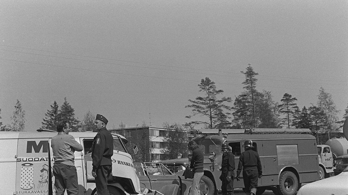 Liikenneonnettomuus moottoritiellä Helsingissä vuonna 1970. Paloauto ja muita autoja kolarissa, poliisi, palomiehiä ja ihmisiä onnettomuuspaikalla. 