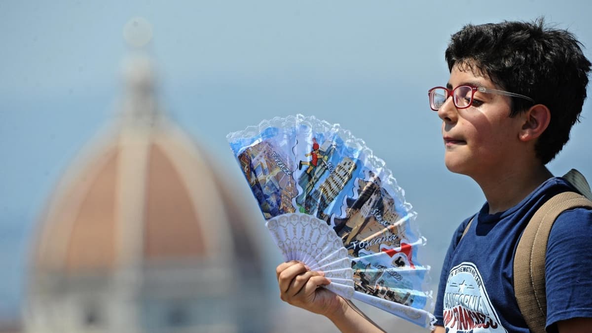 Poika tuulettelee viuhkan kanssa helteessä Italiassa