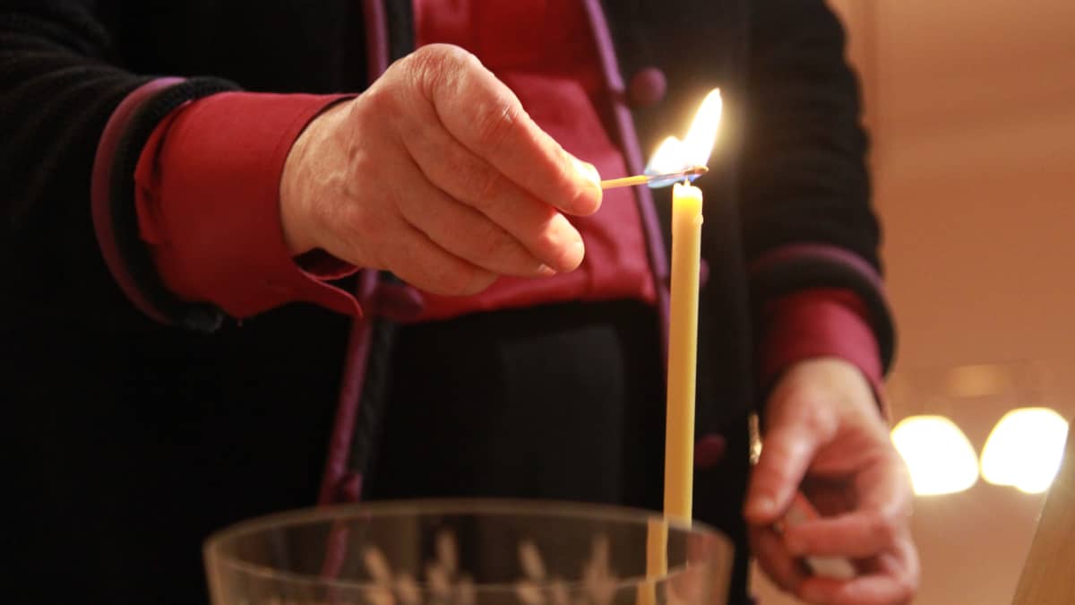 Piispa sytyttää kynttilän.