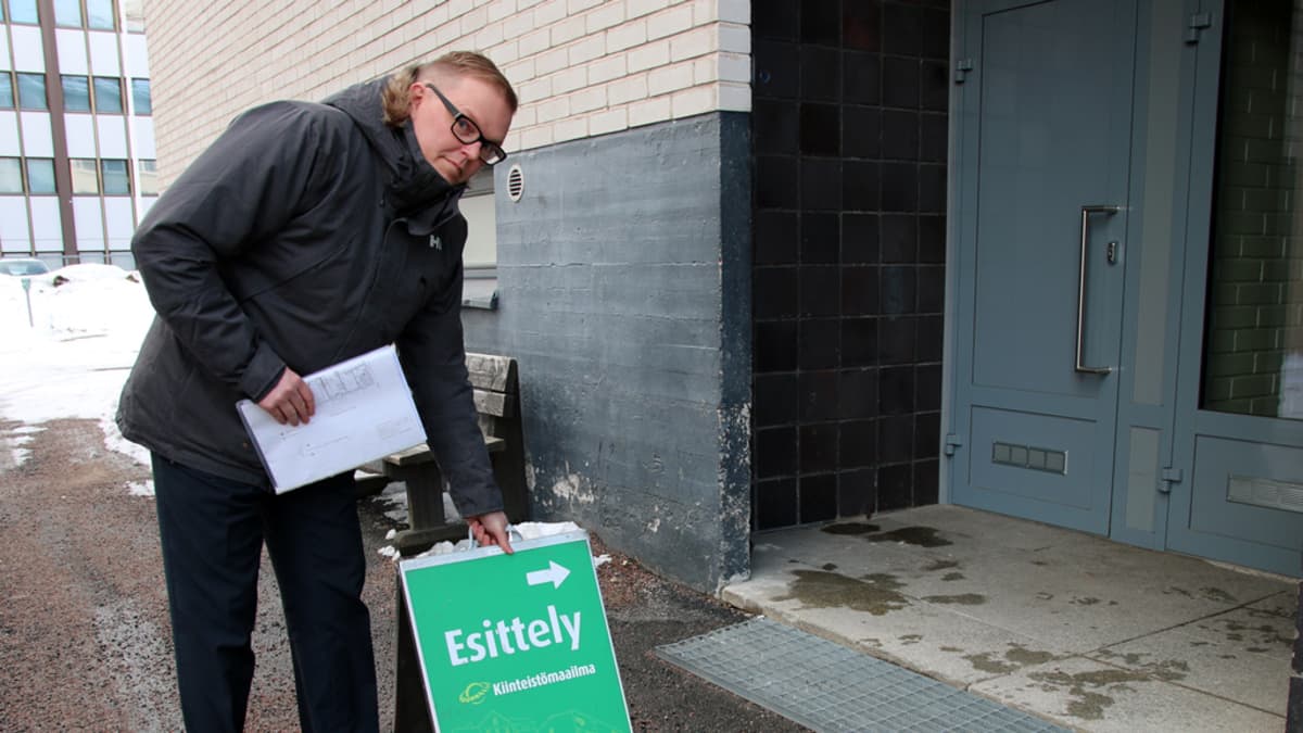 Kiinteistömaailma Rovaniemen toimitusjohtaja Mika Lehtiniemi asettelee vihreää esittelykylttiä talon sisäänkäynnin eteen.