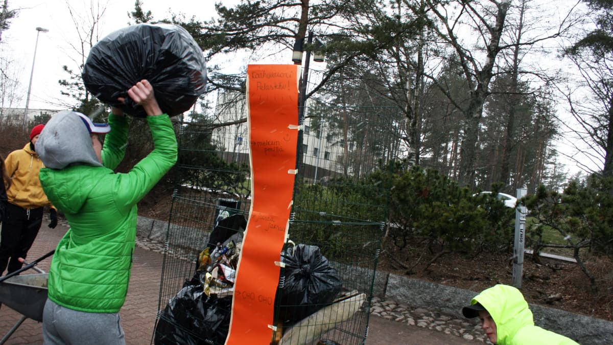 Poika laittaa roskia astiaan.