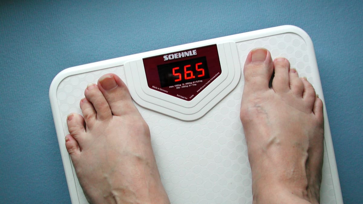 Naisen jalat vaa'alla, jokä näyttää lukemaa 56,5 kiloa.