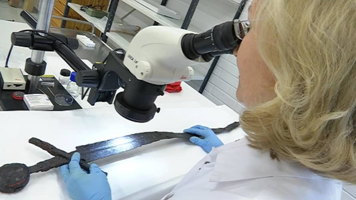 Konservaattori tutkii vanhaa miekkaa