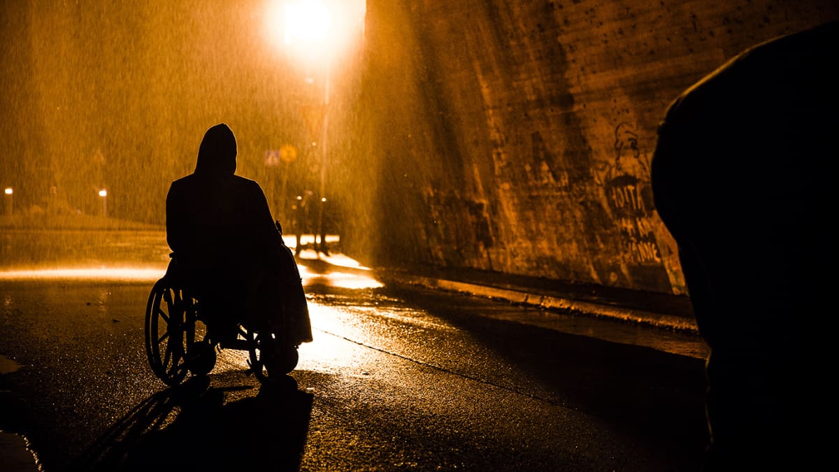 Pyörätuolissa istuvan miehen siluetti tihkusateisessa yössä, otos elokuvasta Rendel