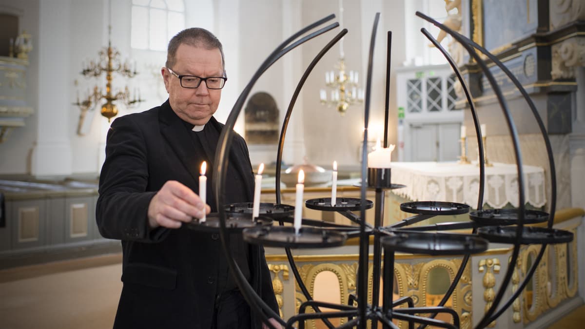 Kirkkoherra Hasse Häggblom sytyttää kynttilän.
