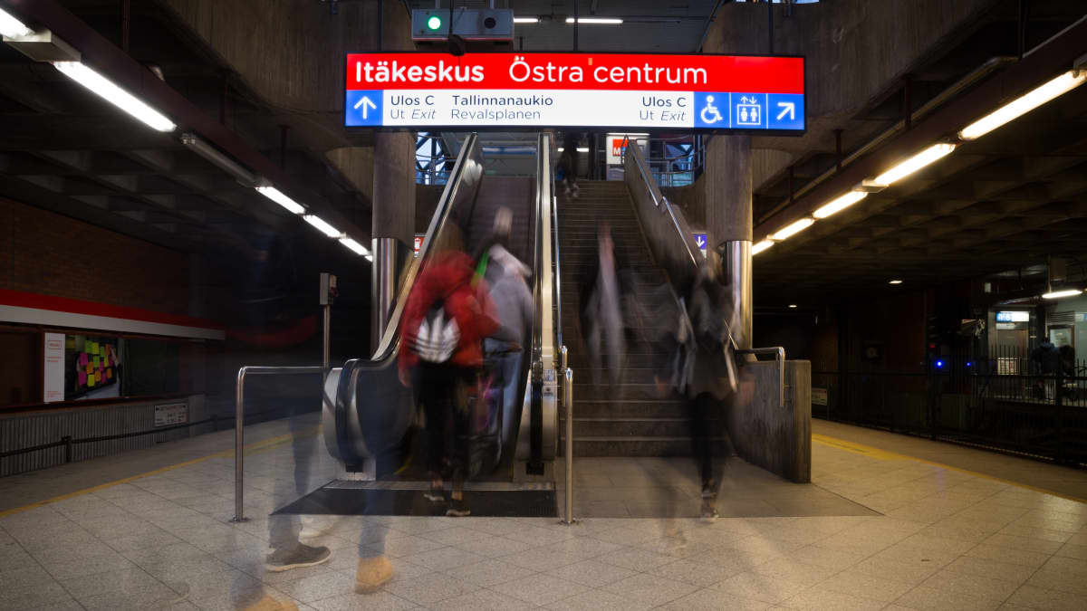 Ihmisiä menee metrolaiturilta rullaportaisiin.