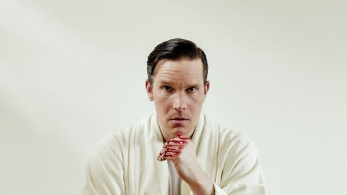 Näyttelijä Martin Bahne istuu näytelmän promokuvassa alusvaatteisillaan jalat kylpylaitteessa, jossa on punaista nestettä.