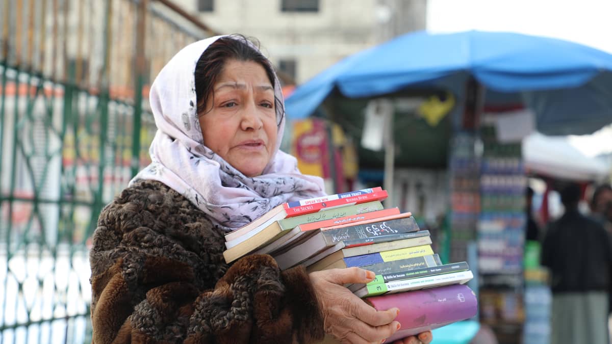 Kirjoja myyvä Fereshta Sadeqi seisoo Kabulin keskustassa. Maan taloudellinen ahdinko tarkoittaa, että asiakkaita ei enää löydy.