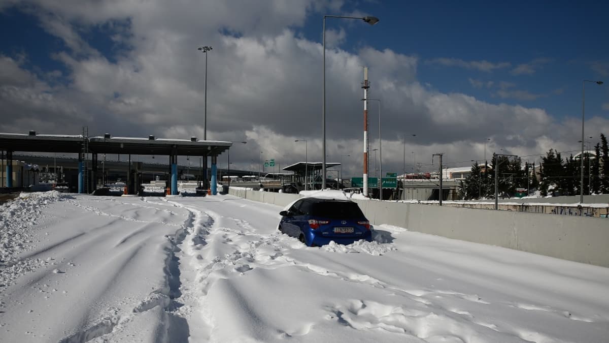 Kuvassa sininen auto lumen täyttämällä tiellä. 