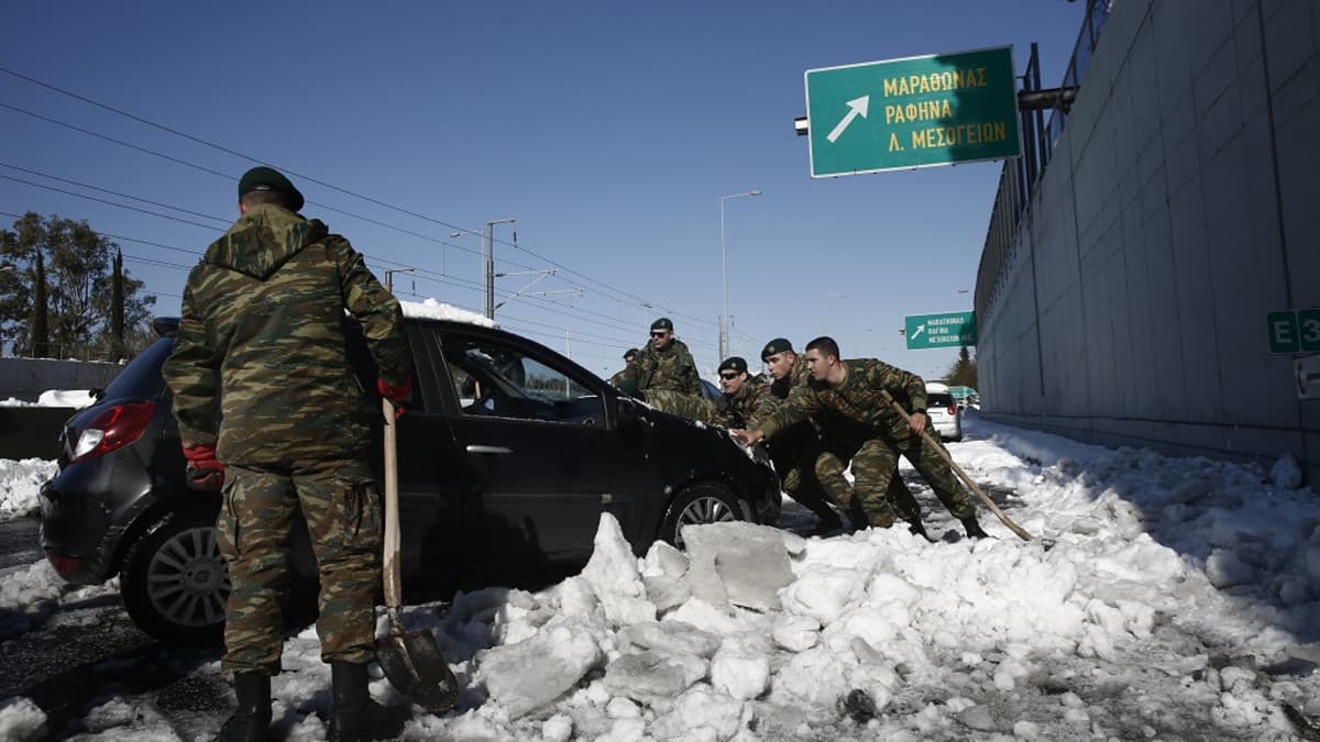 Kuvassa sotilaita työntämässä mustaa autoa. Etualalla seisoo sotilas lapio kädessään. 
