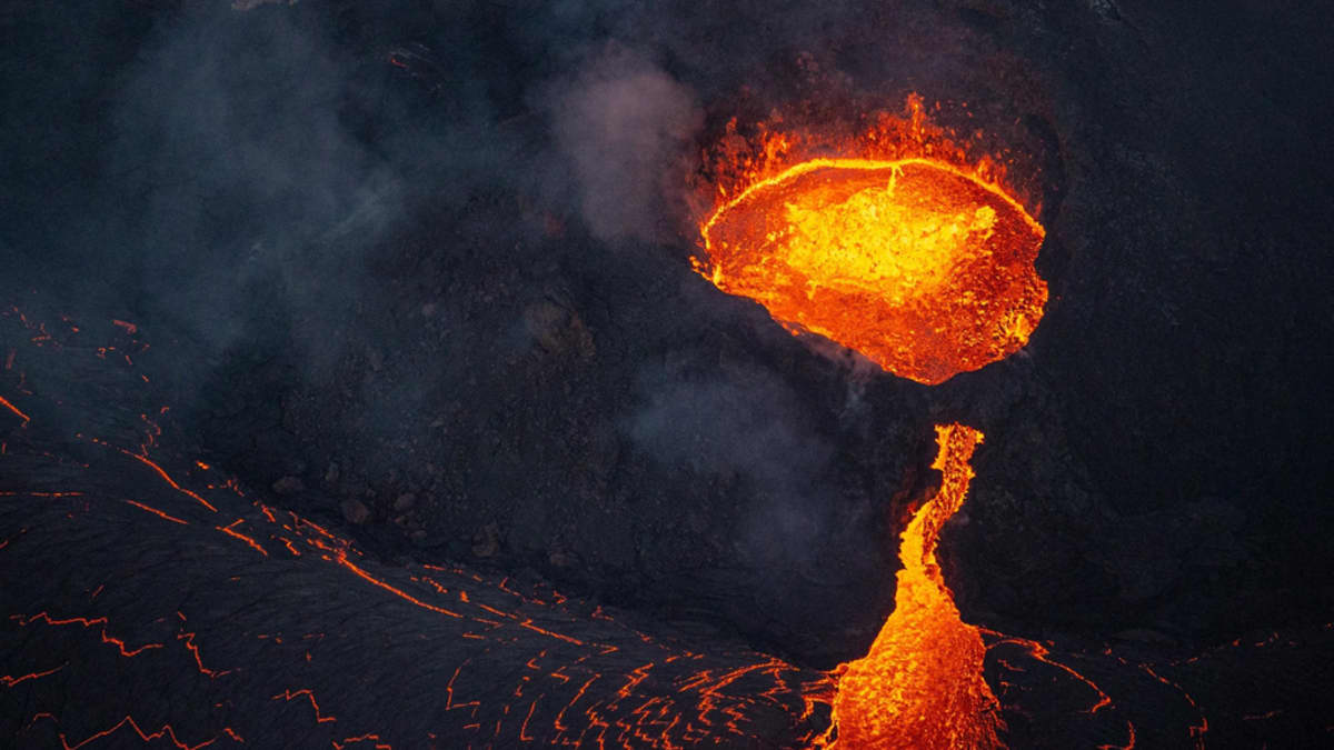 Öinen näkymä tulivuoren kalderan punakeltaisena hehkuvasta laavasta, jota myös valuu rinnettä pitkin mereen, ja ilmassa leijuvasta pyroplastisesta aineesta. 