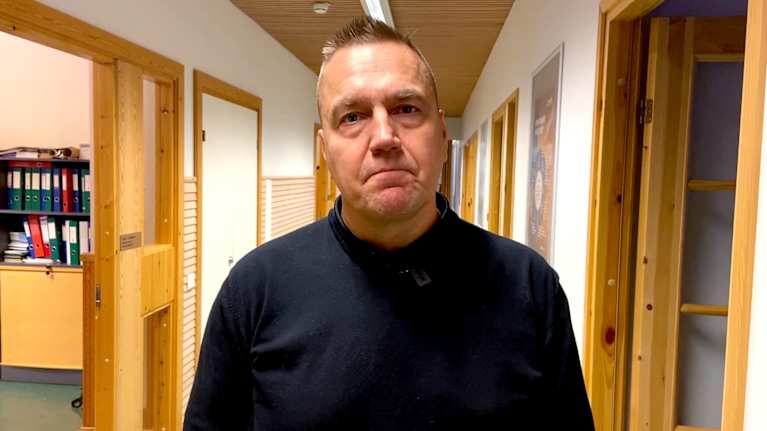 Man i svart tröja står i en korridor.