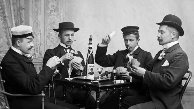 Vanhassa mustavalkoisessa valokuvassa neljä miestä pelaa korttia vuonna 1905. 