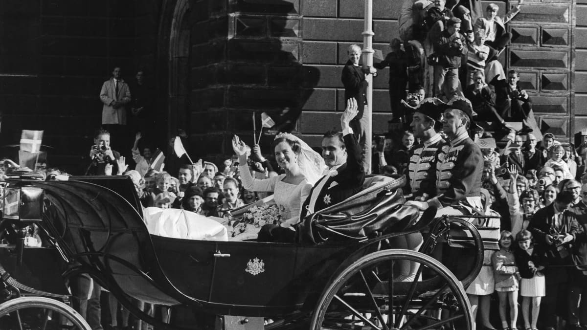 Prinsessa Margarethe ja prinssi Henrik istuvat hääpuvuissaan vaunuissa. Katsomassa on suuri ihmisjoukko.
