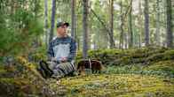 Panu Halme sitter i skogen med en svampkorg bredvid sig.