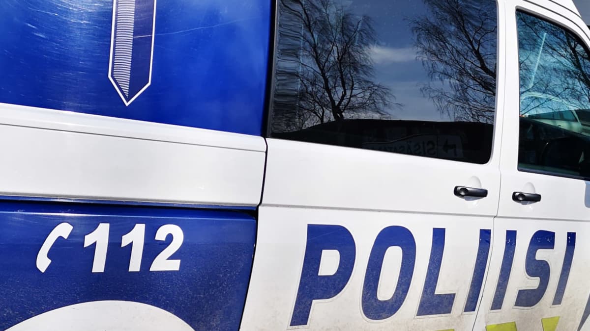 Poliisiauto, jonka ikkunasta heijastuu puita.