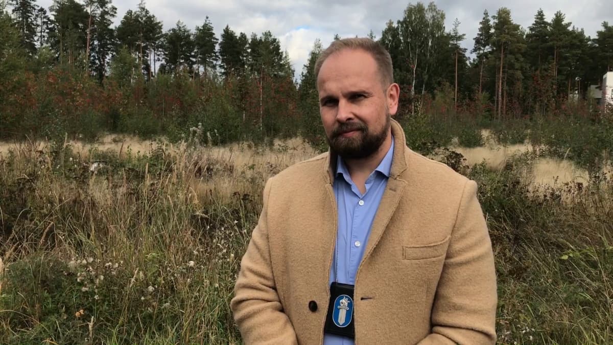 Rikoskomisario Jarmo Katila seisoo syksyisen niityn laidalla kaulassaan poliisin virkamerkki