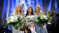 Three beauty queens smile with bouquets and trophies in their hands.