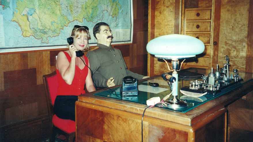 Toimittaja istuu puhelimen luuri korvalla Stalin nuken vieressä Sotshin museossa.