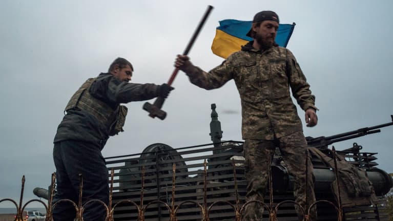 Kaksi sotilasta, joiden taustalla on Ukrainan lippu.