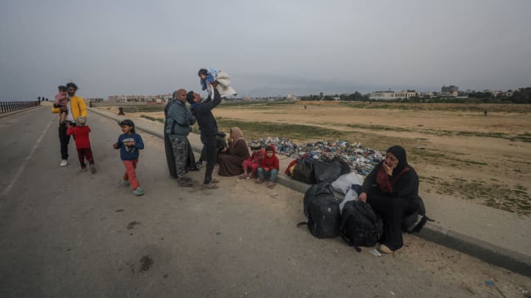 Palestiinalaiset lepäävät ylitettyään rajanylityspaikan Gazan pohjoisosasta etelään Al Rashidin tietä pitkin 26. helmikuuta 2024. 