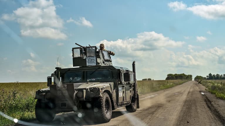 Ukrainalainen sotilasajoneuvo ajaa peltojen ympäröimällä tiellä.