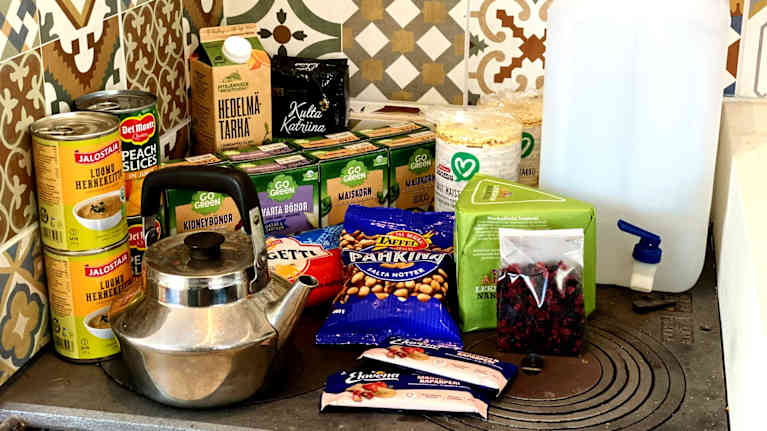 En massa olika livsmedel, en kaffepanna, en vattenkanister som är på en gjutjärnsspis.