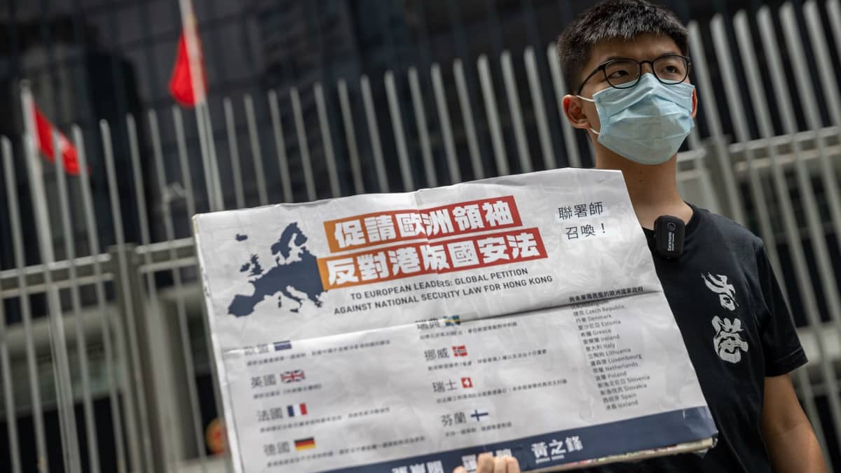 Joshua Wong pitää kädessään kiinankielistä plakaattia