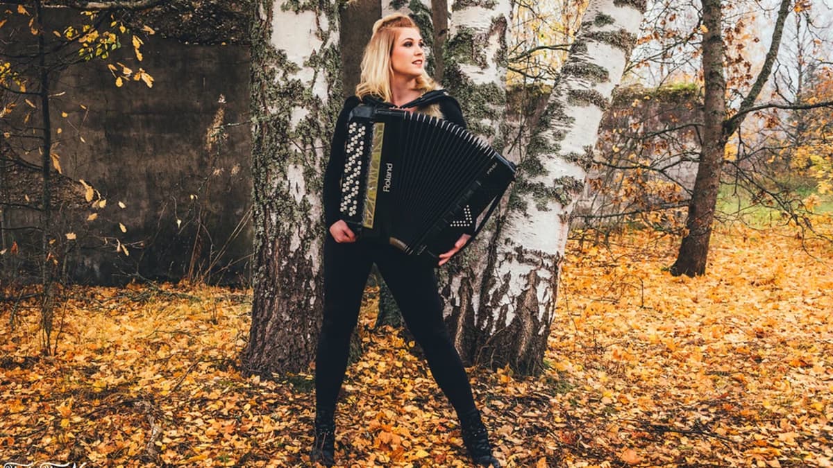 Netta Skog harmonikka sylissään koivikossa.