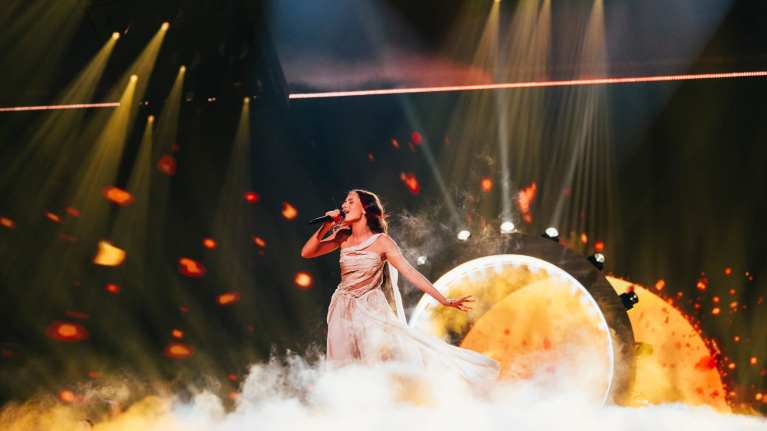 Eden Golan Euroviisuesityksen harjoituksissa lavalla. Laulajalla on valkoinen mekko. Taustalla valorengas.