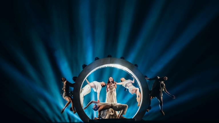 Eden Golan Euroviisuesityksen harjoituksissa lavalla. Laulaja laulaa mikrofoniin pyören renkaan sisällä, jonka sisä kaarella on valot. Ympärillä viisi tanssijaa.
