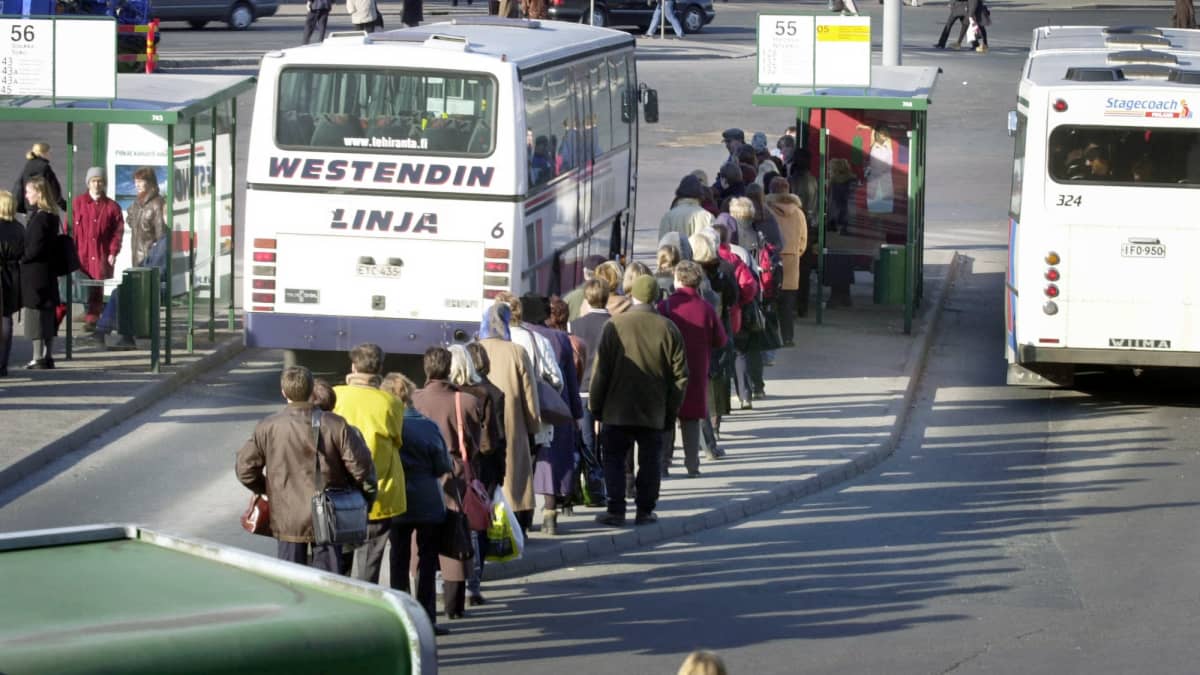 Ihmiset jonottavat paikallisliikenteen bussiin.